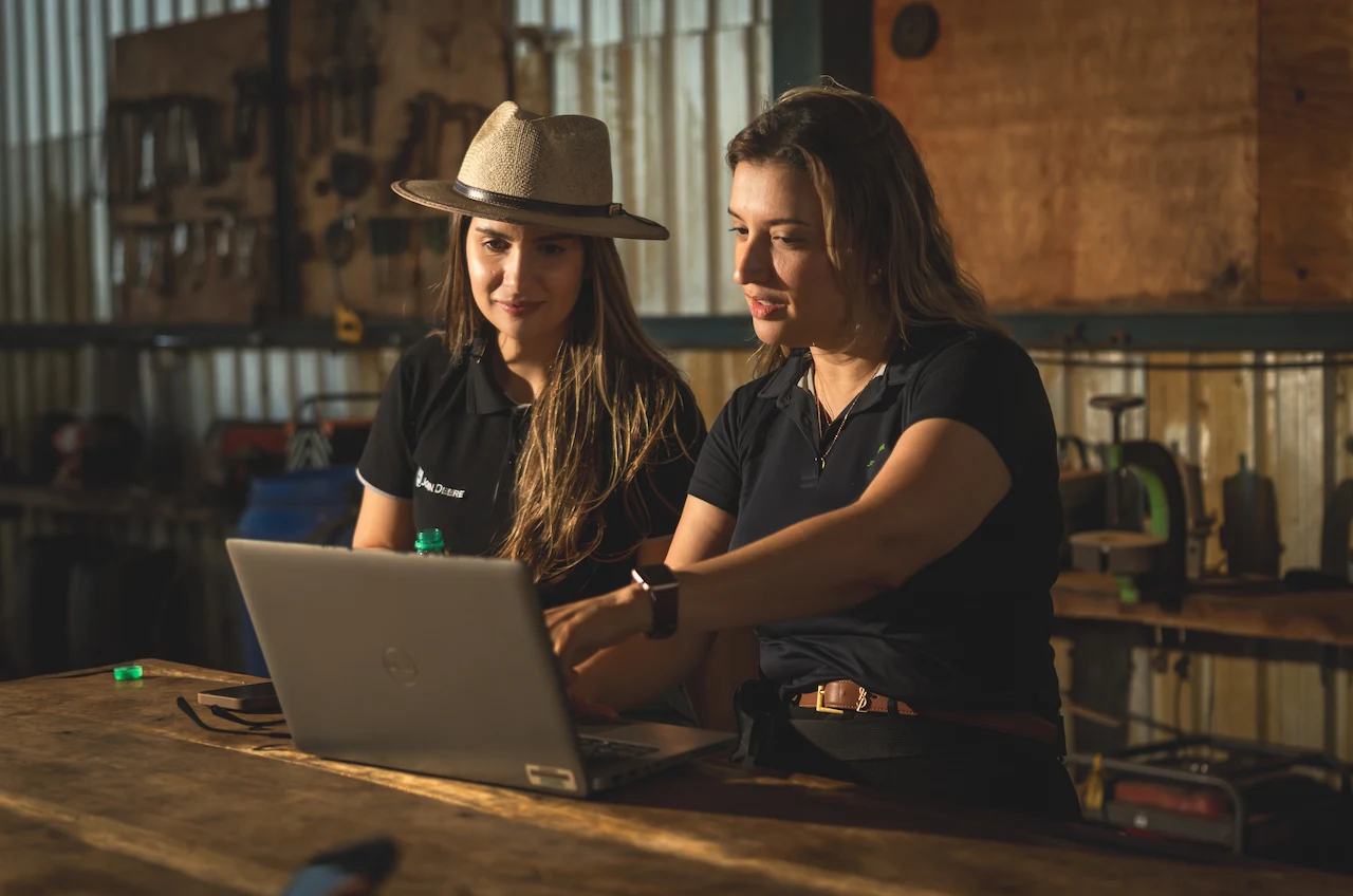 duas mulheres olhando para o computador e discutindo uma renegociação de financiamento agrícola